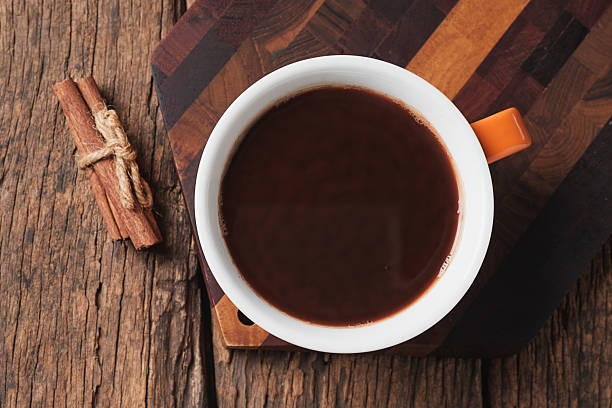Hot chocolate cup with cinnamon sticks on rustic wooden table
