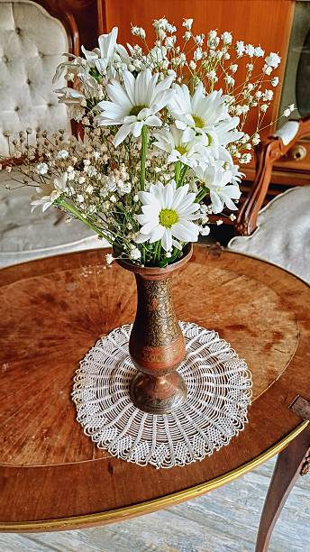 istock There is lace on the coffee table and daisies in an old vase. 2240114317