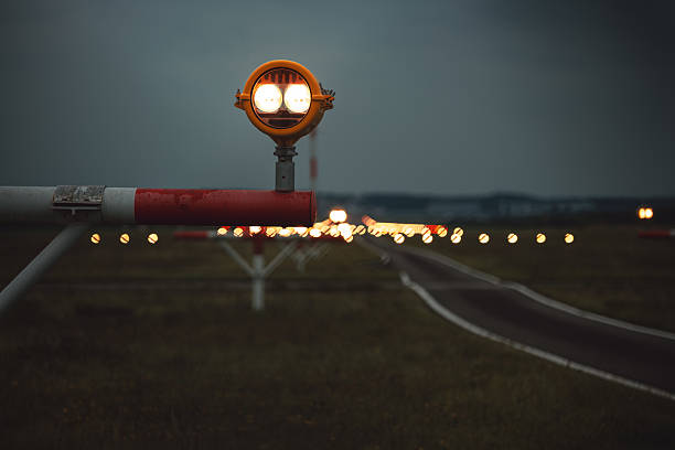 Precision Approach Path Indicator lights in front of an empty airport runway strip and edge lights. Close up shot of the light clusters, dark, moody, cloudy atmosphere, no people