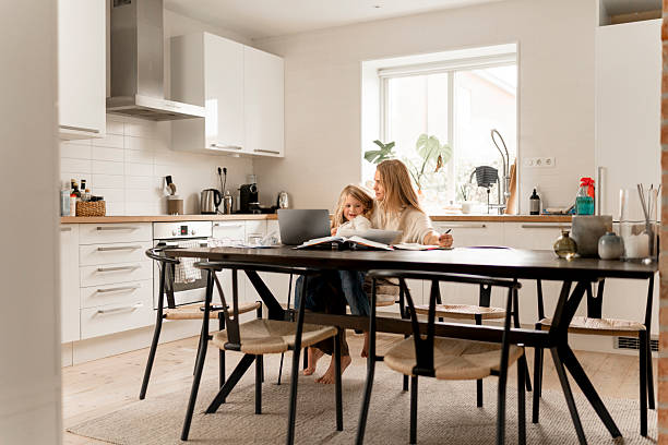 istock Family at home: Scandinavian mother and child study while working on a laptop in the kitchen 2240116079