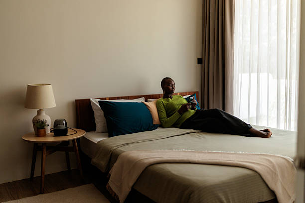 istock Black Woman Relaxing on the Bed Using Her Phone 2240117515