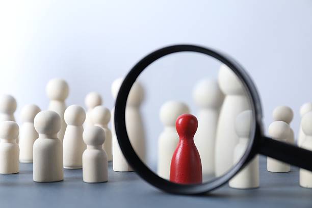 istock Human resources concept. Looking at wooden figures through magnifying glass on table against light background, closeup 2240117581