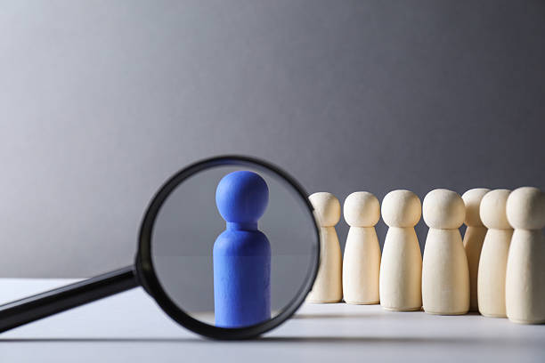 istock Human resources concept. Looking at blue figure through magnifying glass on table against grey background, closeup. Space for text 2240117600