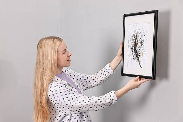 istock Smiling decorator hanging abstract picture on wall indoors 2240117965