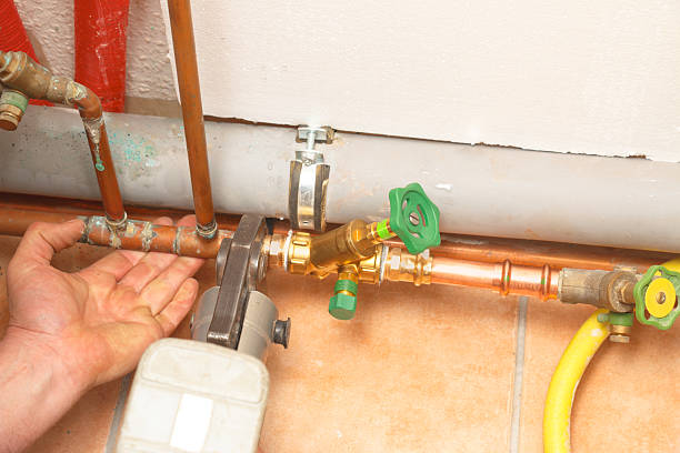 Plumber repairs soldered copper pipe with shut-off valve using modern hydraulic fitting pressing pliers.