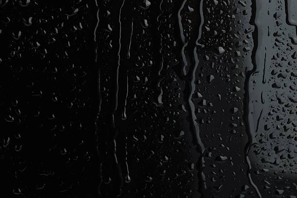 Water drops on black glass surface, closeup