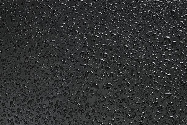 Water drops on dark grey glass surface, top view