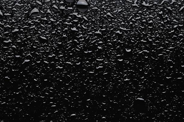 Water drops on black glass surface, top view