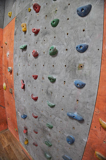 istock climbing wall displays various colorful holds positioned at different heights. wall is part of an indoor rock climbing gym, capturing a moment of activity and excitement 2240126385