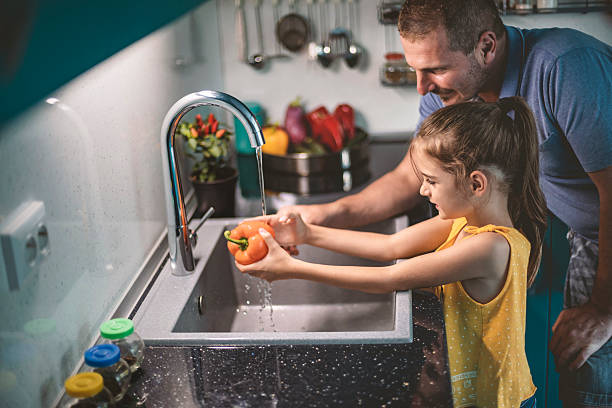 istock Father and daughter washing bell pepper in modern kitchen 2240127182