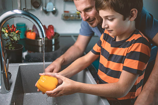 istock Child and parent washing vegetables in cozy kitchen 2240127197