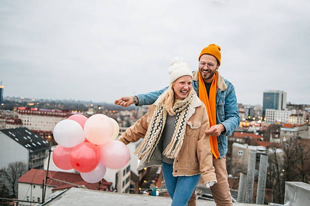 Young couple celebrating love with balloons on a rooftop stock photo