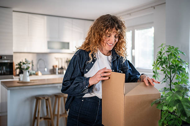 istock Happy woman unpacking moving boxes in new kitchen 2240129297