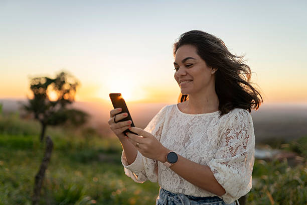 istock Woman using a smartphone in nature at sunset 2240129524