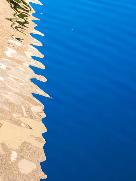 istock Abstract water surface reflecting natural light and colors of a building, creating rippling patterns over deep blue liquid, forming a textured background 2240131064