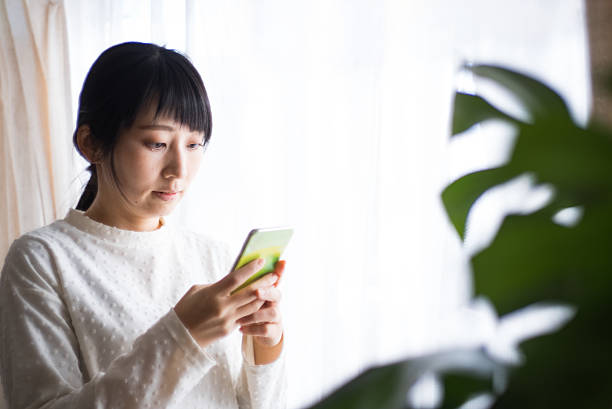istock A Japanese woman is looking at her smartphone screen inside a room. 2240131237
