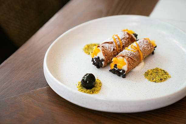 Italian cannoli dessert with ricotta cream, chocolate chips, and orange zest on a white plate