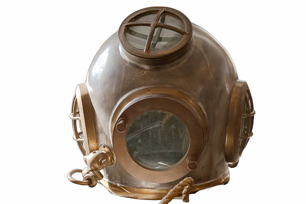 A vintage deep sea diving helmet rests on display in a museum, illustrating the evolution of underwater exploration equipment. The helmet features glass windows and a metal structure.