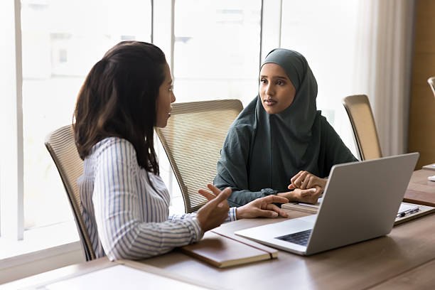 istock Multicultural businesswomen having conversation seated at table with laptop 2240137927