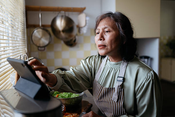 istock Elderly Woman Using Tablet to Follow Recipe in Kitchen 2240137939