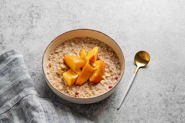 istock Oatmeal with peaches and nuts  in a bowl on a gray background with honey 2240138324