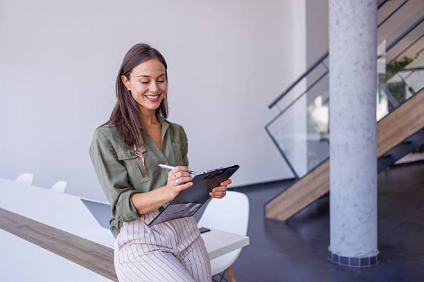 istock Businesswoman writing on clipboard in modern office 2240141043