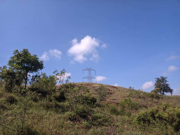 istock power line tower stands on a grassy hill under a bright blue sky 2240141904