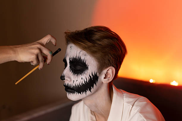 istock a young guy gets Halloween makeup as a scary skeleton. 2240142068
