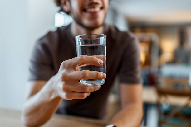 istock Man drinking a glass of water at home 2240142845