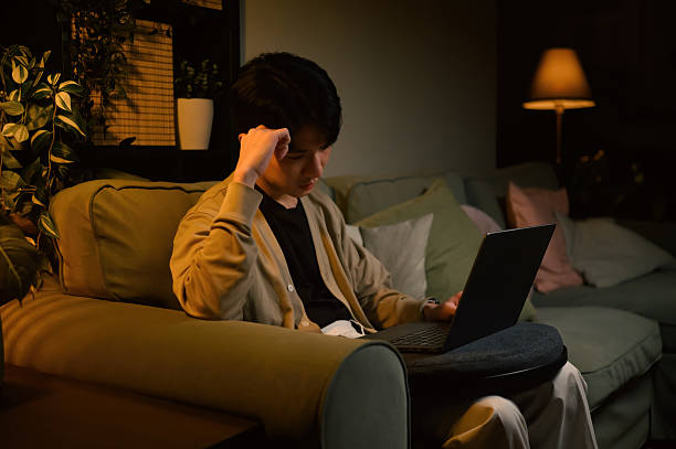 istock Exhausted remote worker focusing on a laptop in dark home, experiencing stress from workload 2240144430