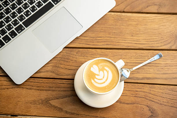 Laptop and a cup of coffee on a table in a street cafe. Remote work concept. Top view