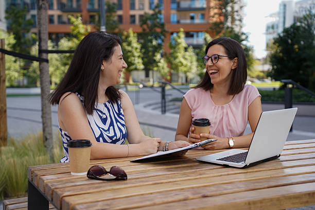 istock Two Young Women Working and Socializing Outdoors with Laptop and Coffee 2240153581