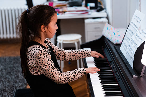 istock Little girl playing piano learning music lesson 2240155062
