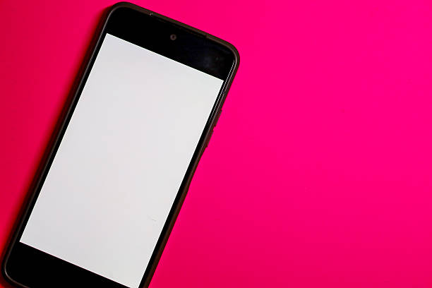 This minimalistic shot shows a smartphone with a white screen, positioned diagonally in the bottom left corner. The gadget rests on a saturated fuchsia or magenta background,