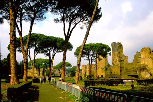 A 2002 slide film capture of ancient Roman ruins in Ostia Antica, Italy. Weathered brick walls and broken marble columns rise under a clear blue sky, framed by greenery and bathed in warm analog tones. The image evokes the quiet grandeur of a once-thriving Roman port city, preserved in stone and memory through the lens of early 21st-century travel.
