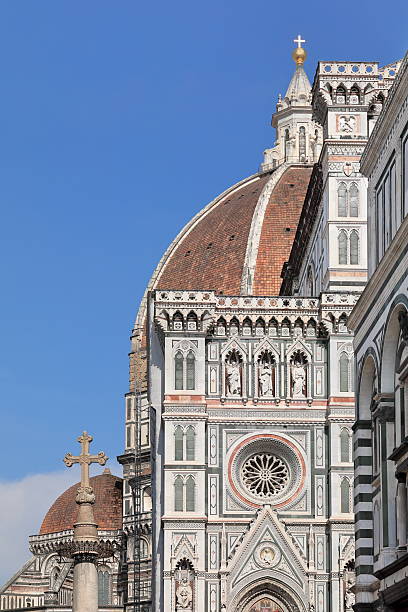 Florence, Italy-May 17, 2022: Eastward view along the Battistero San Giovanni Baptistery north wall to the Saint Zenobius column upper part and the Duomo's cupola jutting above its north nave facade.