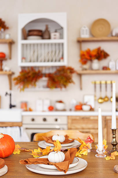 istock Dinning table setting for fall dinner, with pumpkins, leaves, and candle on kitchen background 2240159425