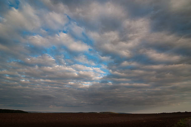 beautiful blue sky with clouds, space above a plowed field