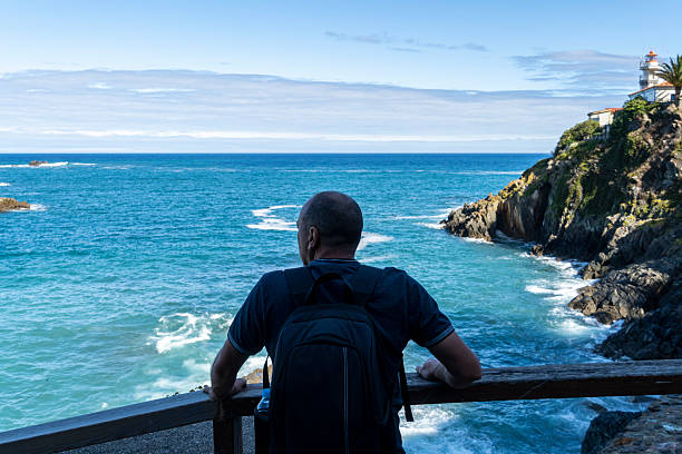 A man gazes out at the ocean from a viewpoint, Cudillero, Asturias, Spain