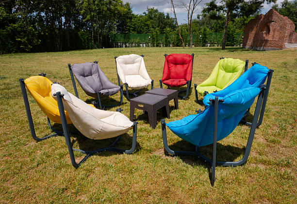 istock Colorful chairs sit empty on the green grass in the backyard. Soft empty chairs to relax and chat with friends in the park 2240163300