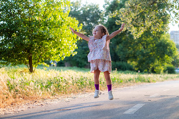 Fashion kid concept - stylish little girl child jumping, wearing bright clothes and sunglasses against the white wall