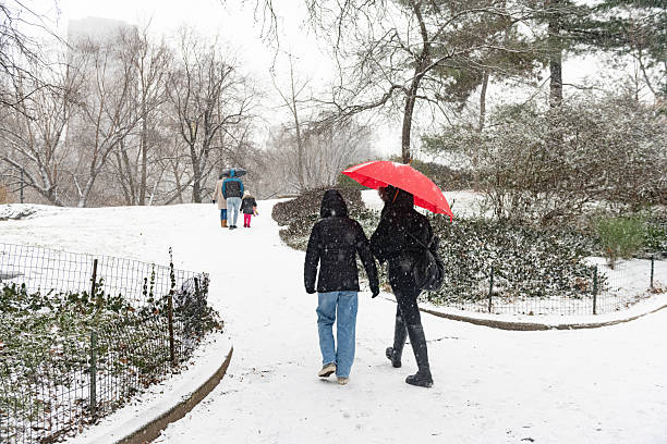 New York City, NY, USA: January 6th, 2025 - People dress for the weather and walk outdoors in the snow on a cold winter day in Central Park
