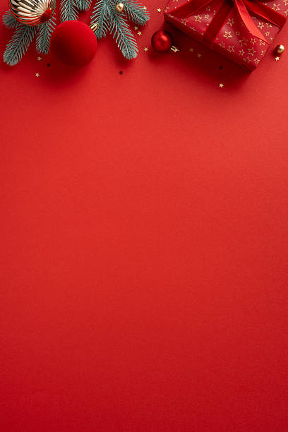 istock A vertical warm red backdrop frames a border of pine branches, a wrapped gift, and glittering ornaments, perfect for Christmas and New Year greetings, celebrations, and holiday decor ideas 2240173119