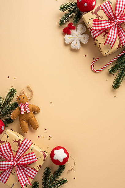 istock Vertical holiday scene with Christmas gift boxes, red ribbon, a teddy bear, candy cane, snowflake ornament, and evergreen branches on a warm beige background 2240173130