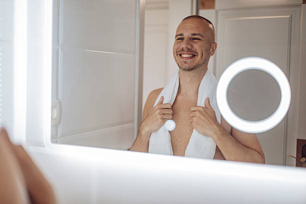 istock Confident Man Smiling at His Reflection in Bathroom Mirror 2240173430