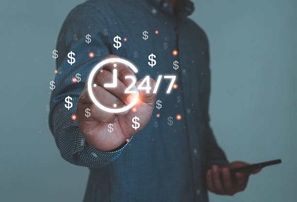 istock Businessman using digital 24 hour, 7 day service icon with dollar symbols, representing online finance, e-commerce and global business working all day, modern technology concept for financial success. 2240175251
