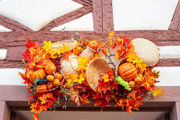 A festive autumn decoration featuring pumpkins, gourds, and colorful fall leaves arranged in woven baskets