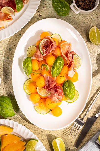 istock Melon prosciutto salad with fresh basil and lime wedges 2240176340