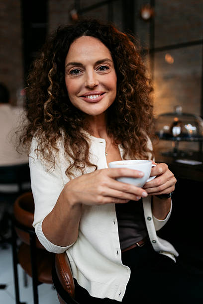 istock Smiling woman holding coffee cup in cafe 2240179647
