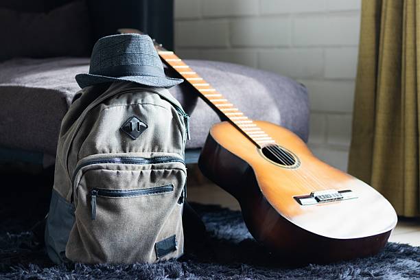 a backpack, a hat, and a guitar ready to travel